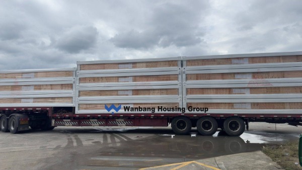 Flat-pack container house units being loaded into a 40ft HQ shipping container
