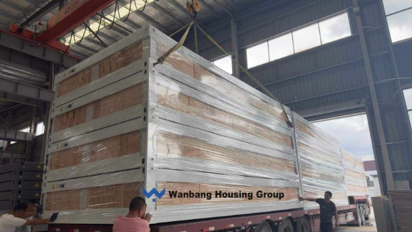 Flat pack container houses being loaded into a 40ft container at a Chinese factory — packing efficiency determines freight cost per unit